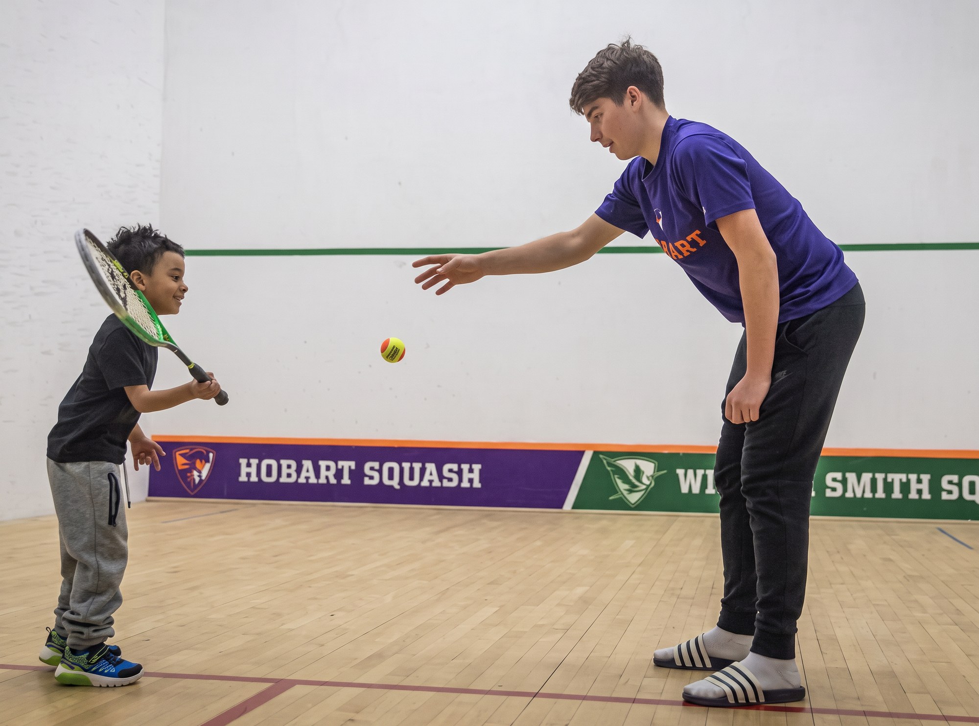 Coach feeding a ball to a junior player during a private lesson